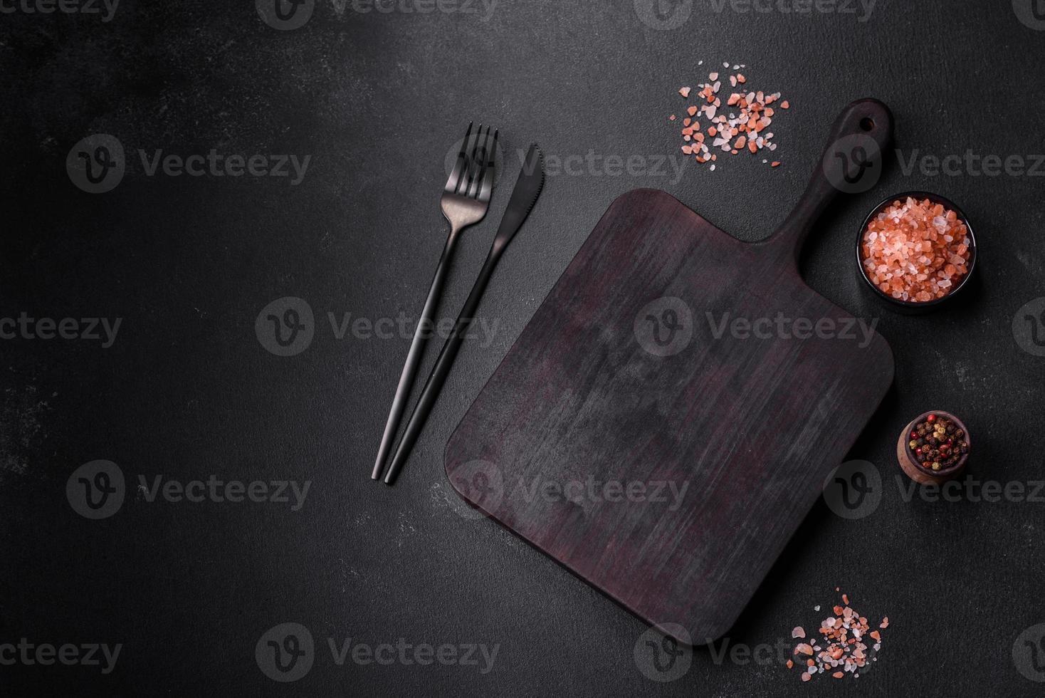 Wooden cutting board with kitchen appliances on a black concrete background photo