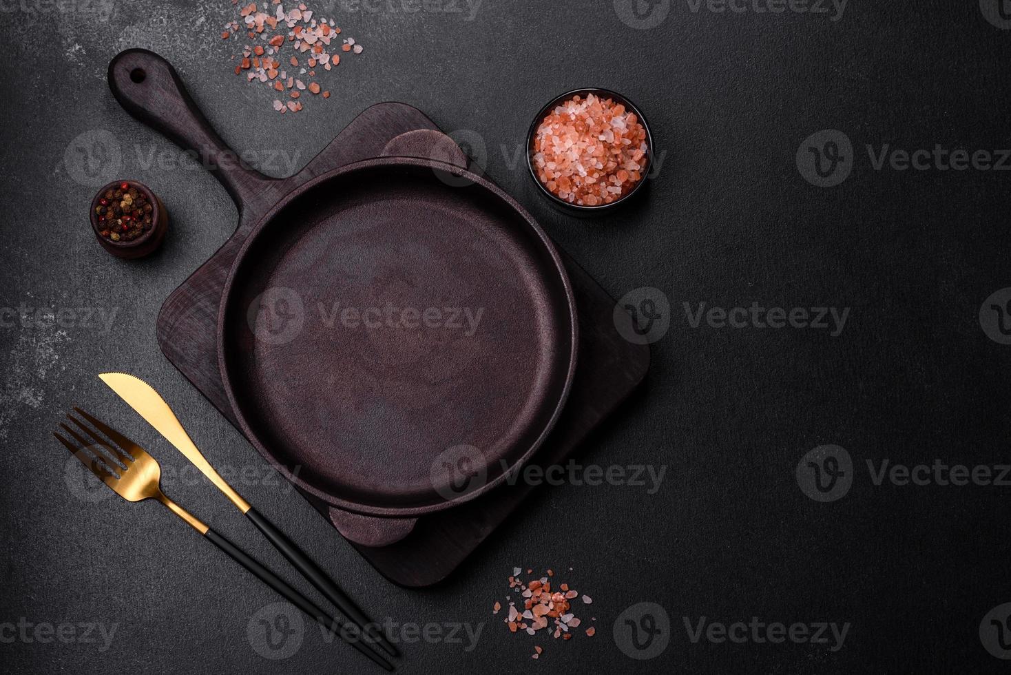 Brown iron empty pan with kitchen utensils on a dark concrete background photo