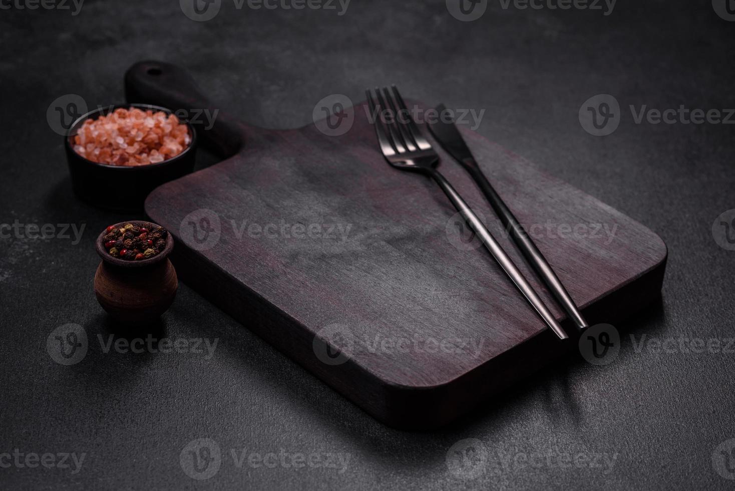Wooden cutting board with kitchen appliances on a black concrete background photo