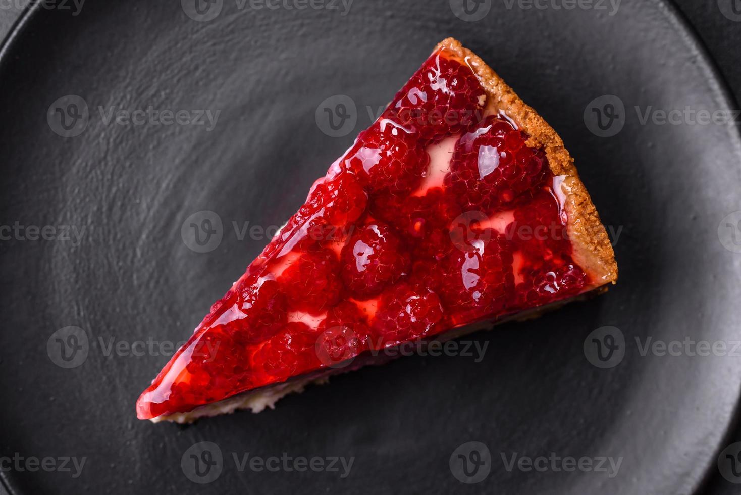 Homemade tasty cheesecake with jelly and raspberry berries on a black plate photo