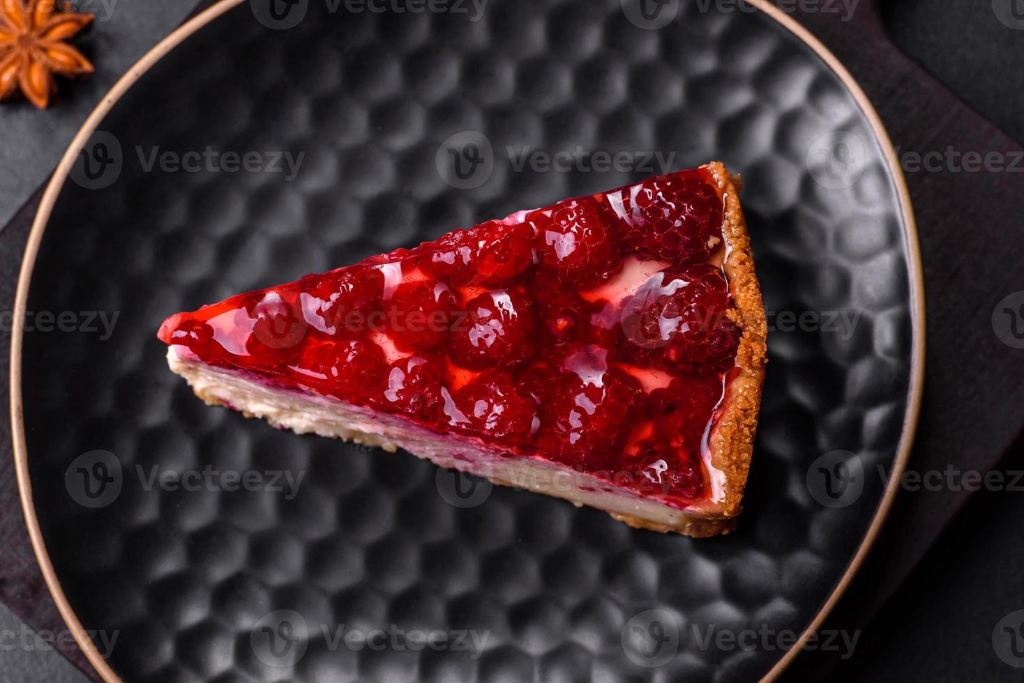 Homemade tasty cheesecake with jelly and raspberry berries on a black plate photo