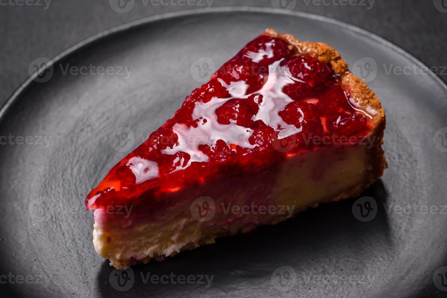 Homemade tasty cheesecake with jelly and raspberry berries on a black plate photo