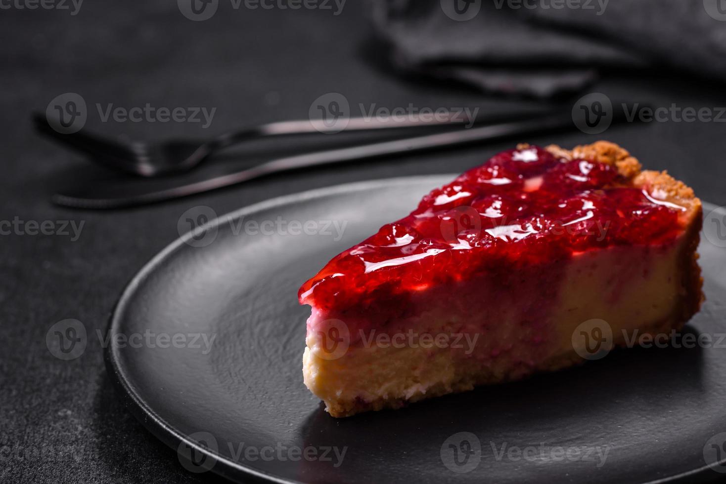 Homemade tasty cheesecake with jelly and raspberry berries on a black plate photo