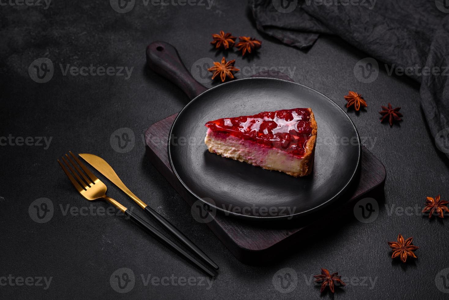 Homemade tasty cheesecake with jelly and raspberry berries on a black plate photo