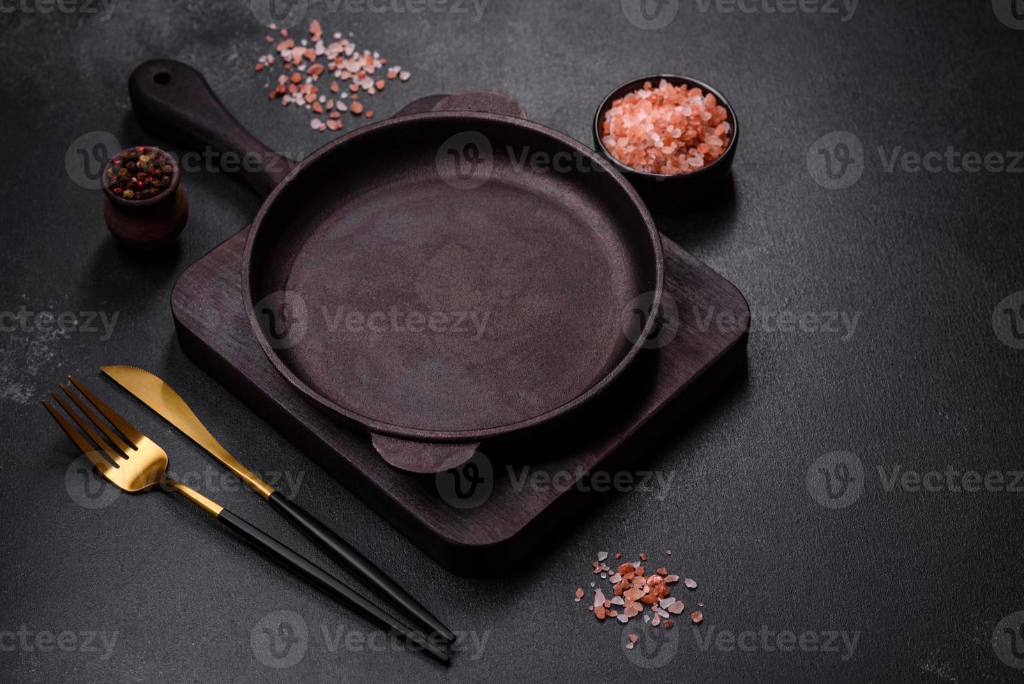 Brown iron empty pan with kitchen utensils on a dark concrete background photo