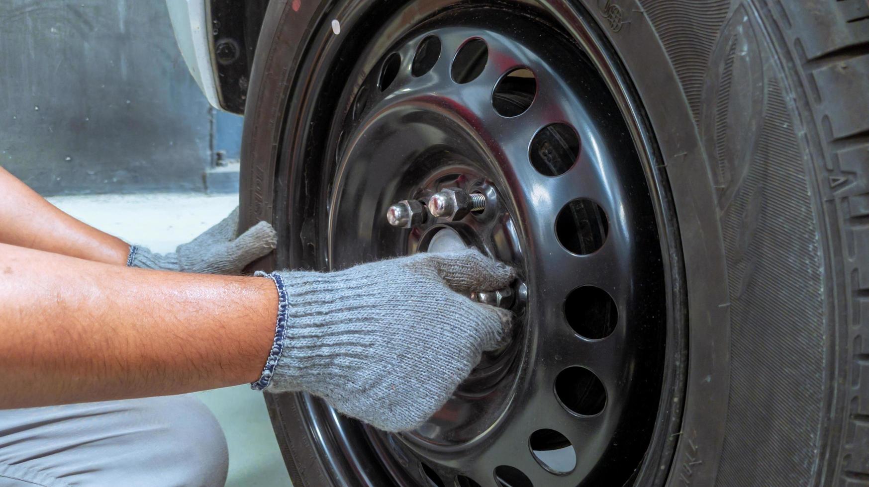 la mano de un mecánico con guantes está arreglando un neumático de camión, cambiando un neumático de camión en un taller de reparación foto