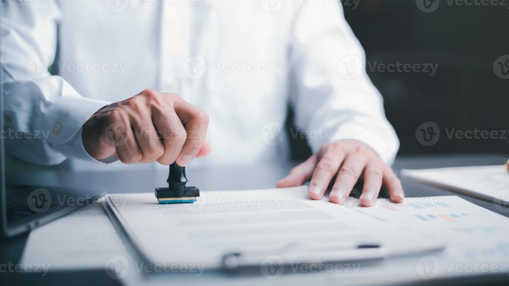Businessman validates and manages business documents and agreements, signing a business contract approval of contract documents confirmation or warranty certificate,approval stamp photo