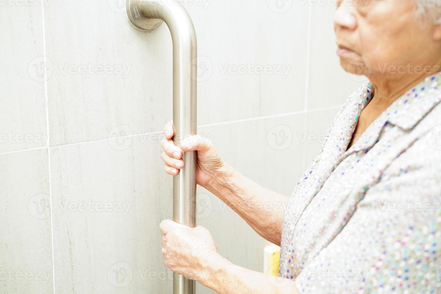 Asian elderly old woman patient use toilet support rail in bathroom, handrail safety grab bar, security in nursing hospital. photo