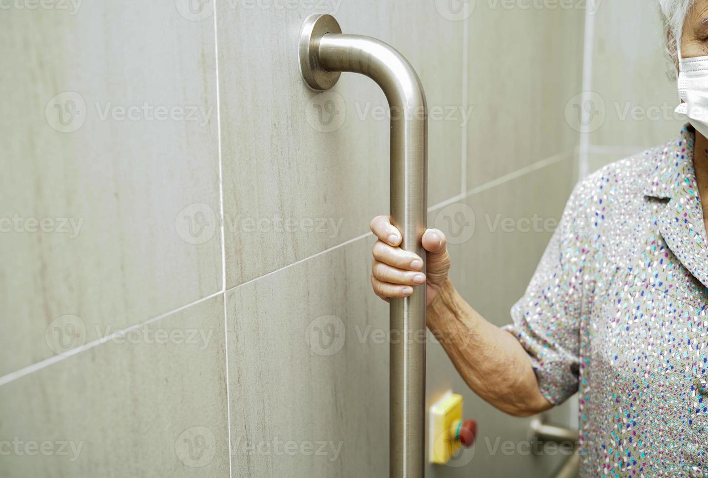 Asian elderly old woman patient use toilet support rail in bathroom, handrail safety grab bar, security in nursing hospital. photo