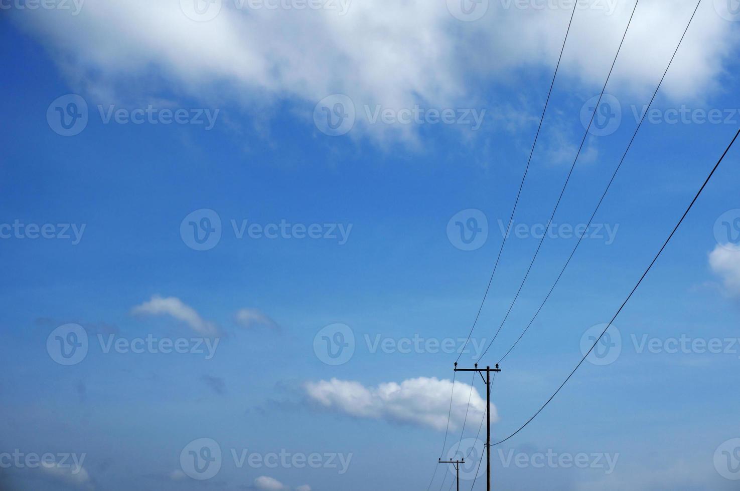 Electric pole power lines outgoing electric wires againts on cloud blue sky. photo