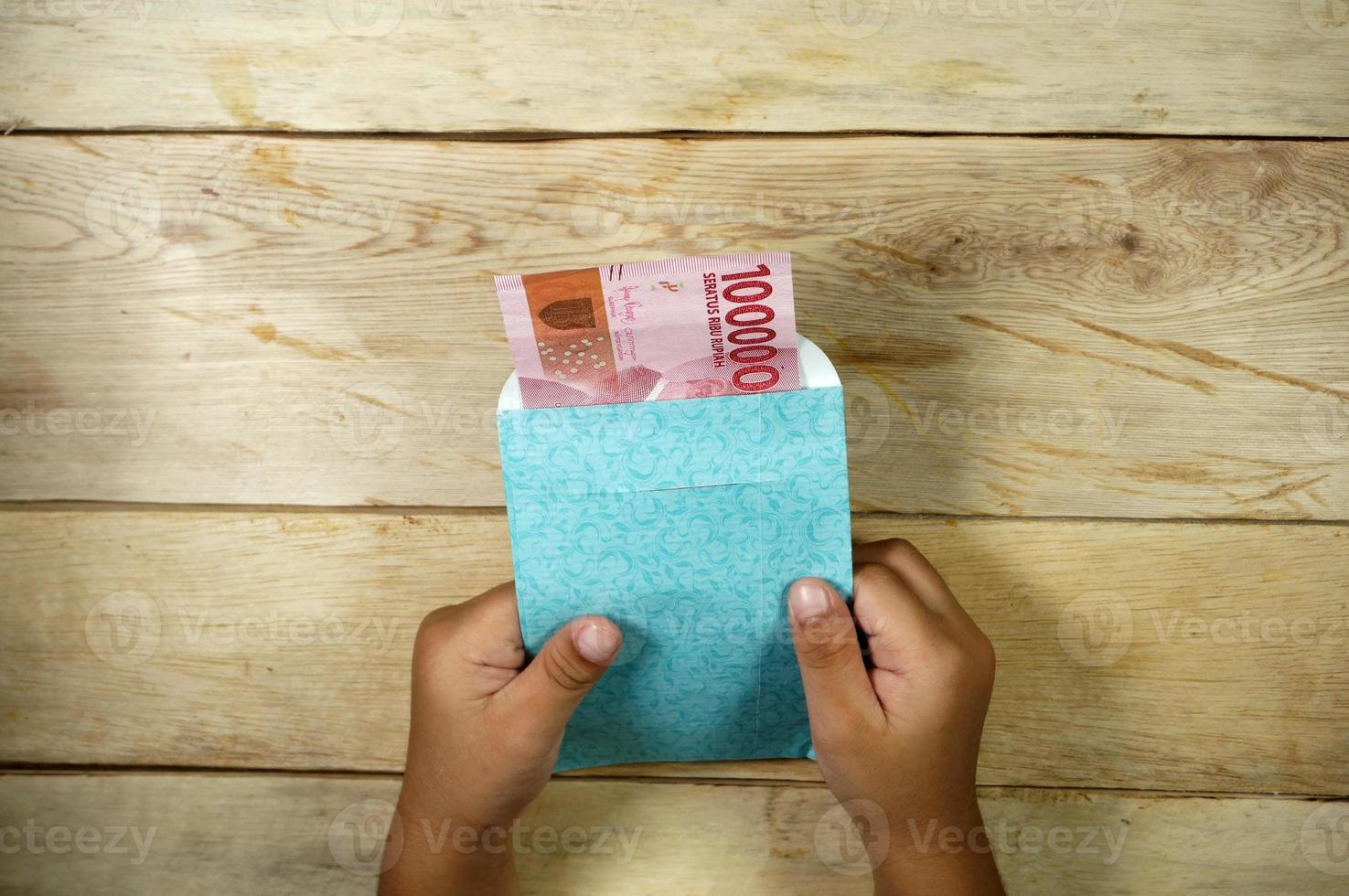 Hand of young kid holding indonesian money. Rupiah, IDR money. photo