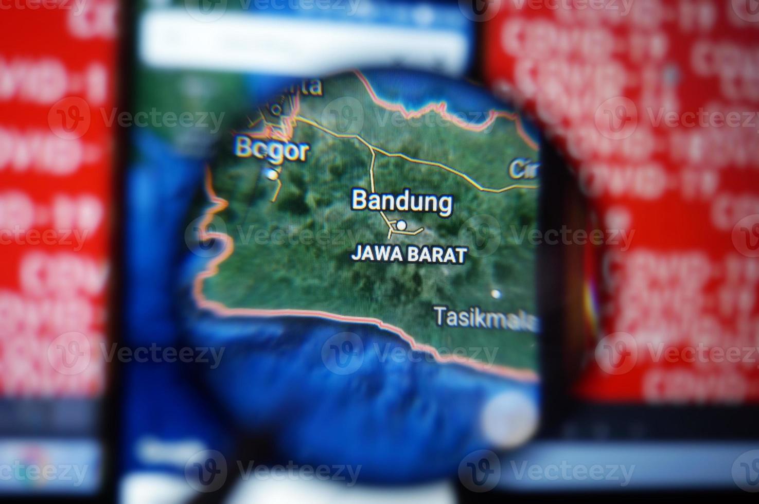 bandung, java occidental, indonesia en google maps bajo lupa con fondo de texto rojo covid-19. foto