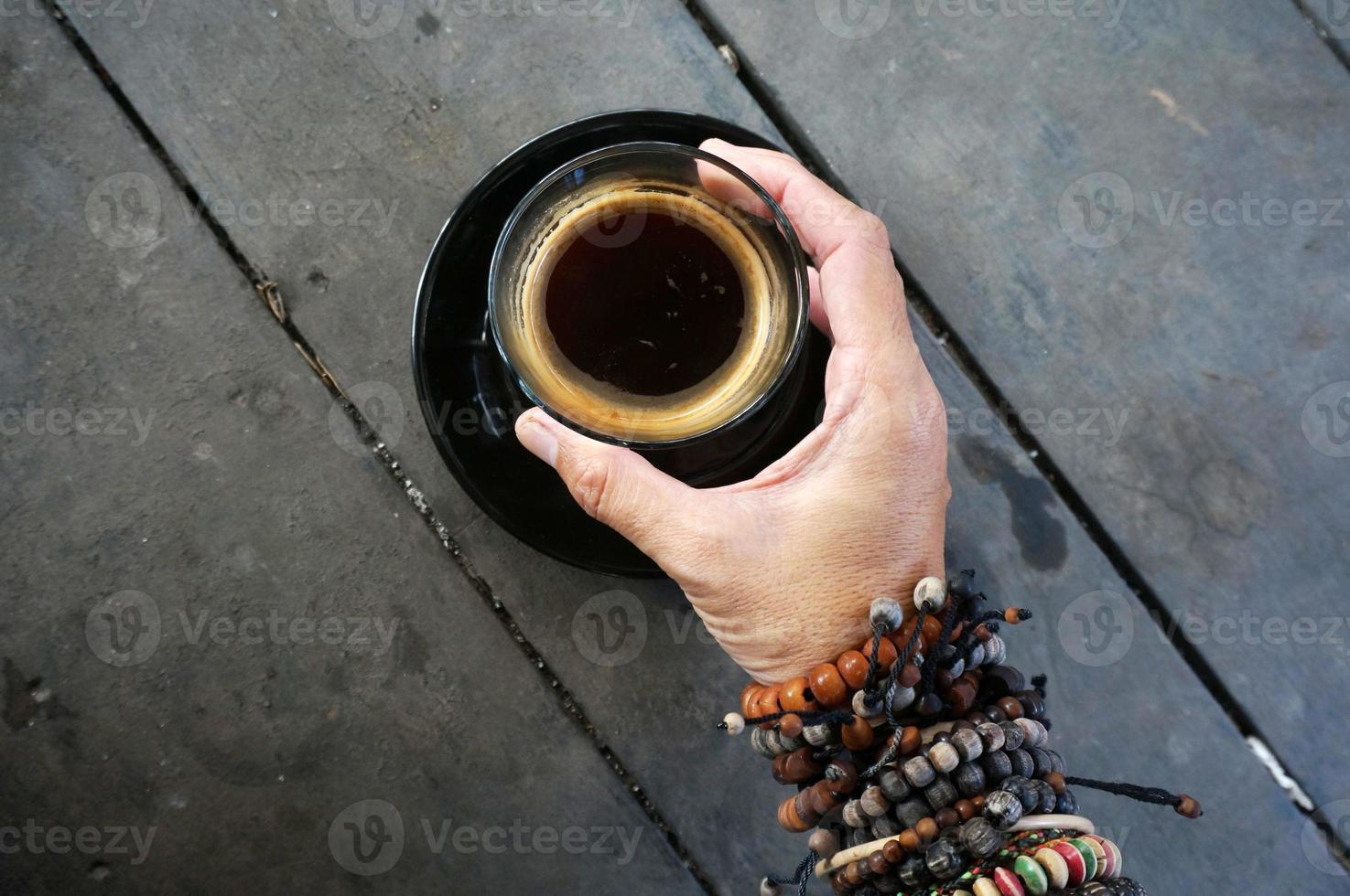 Woman hand holding robusta americano hot coffee on glass. photo