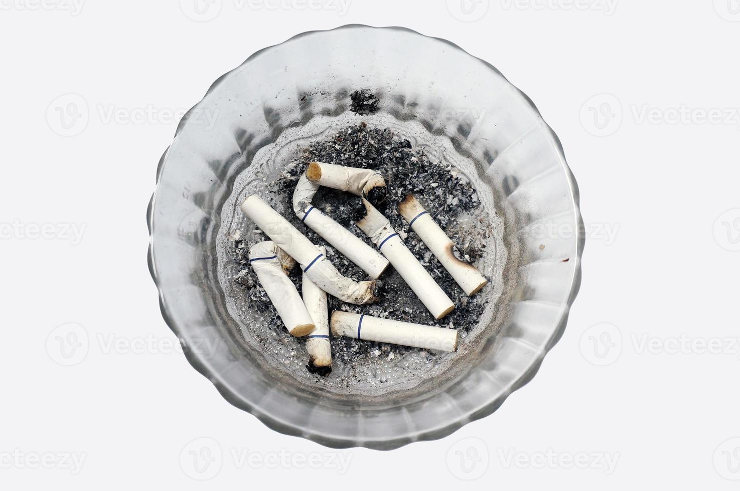 Cigarette butts in a glass ashtray photo