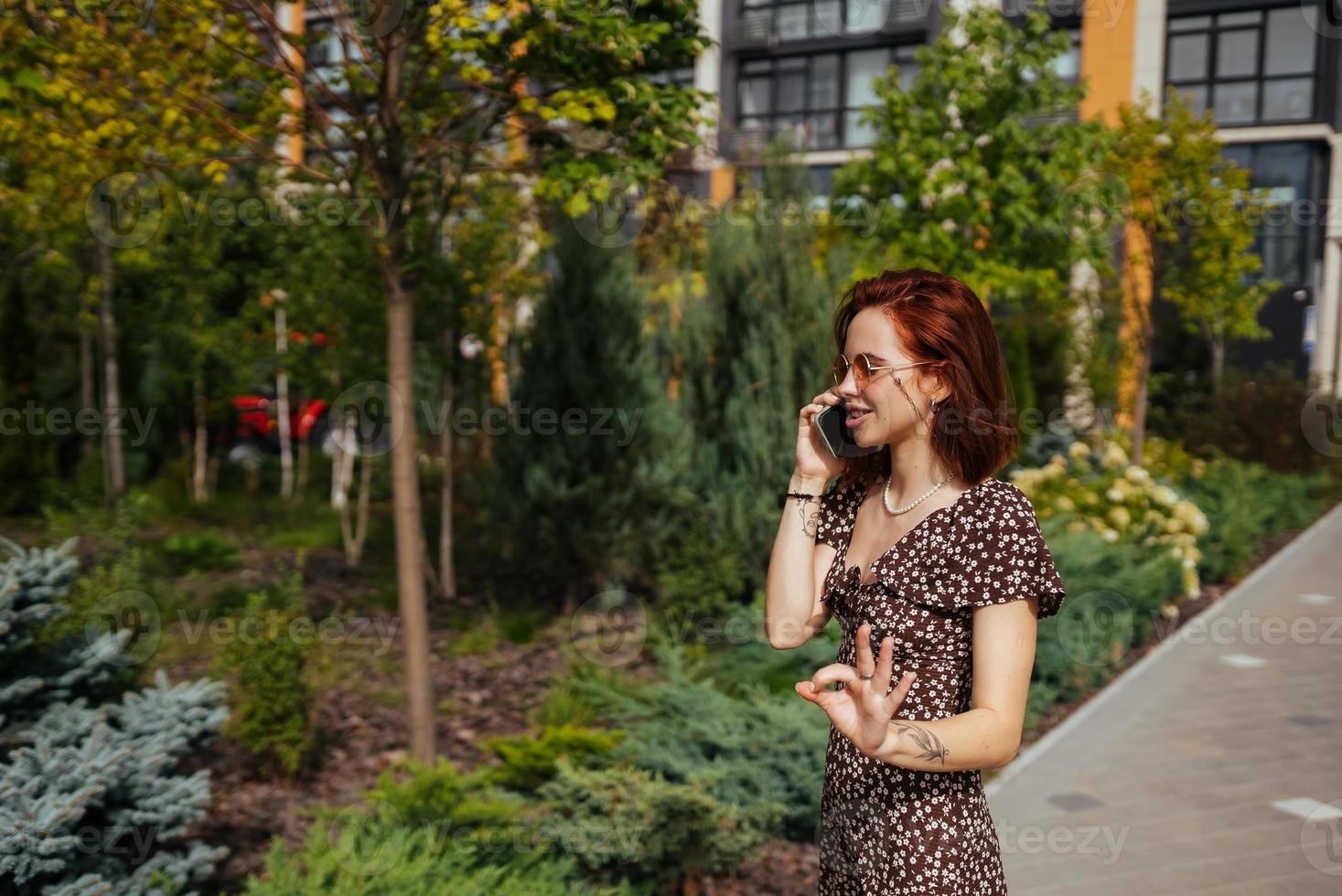 Cute girl talking on mobile phone on modern city background photo