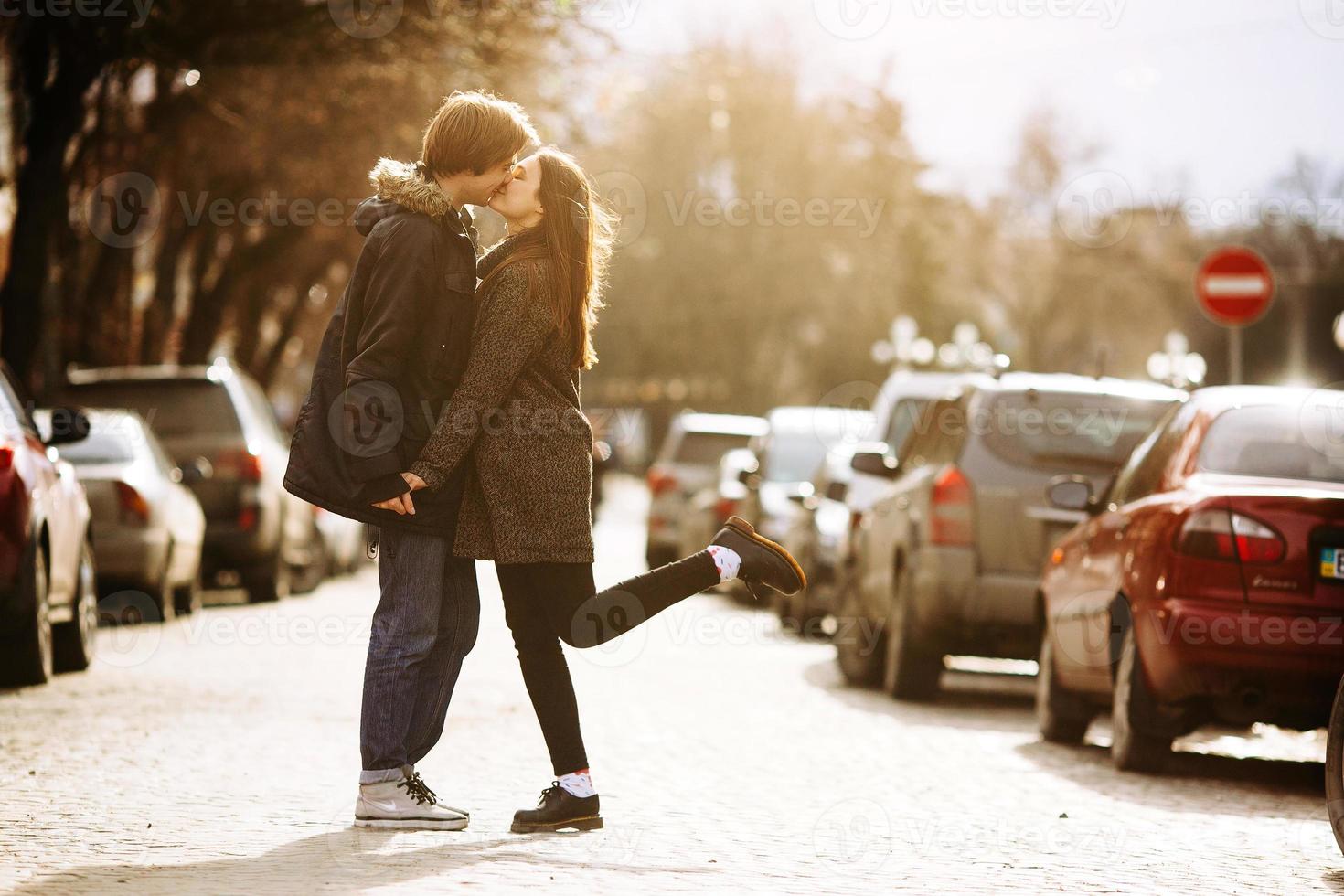 chico y la chica besándose en la calle de la ciudad foto