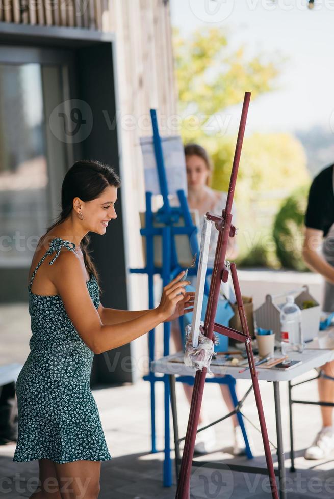 Young woman artist paints with a spatula on the canvas photo