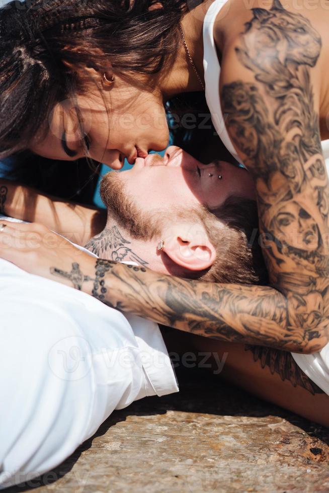 una pareja joven está tumbada en el muelle junto al mar foto