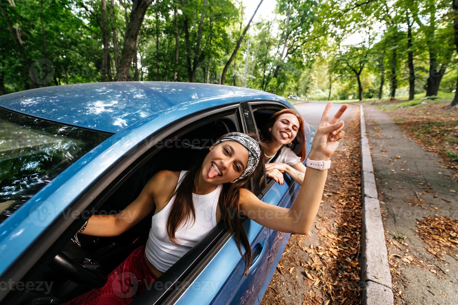 Two girlfriends fool around and laughing together in a car photo