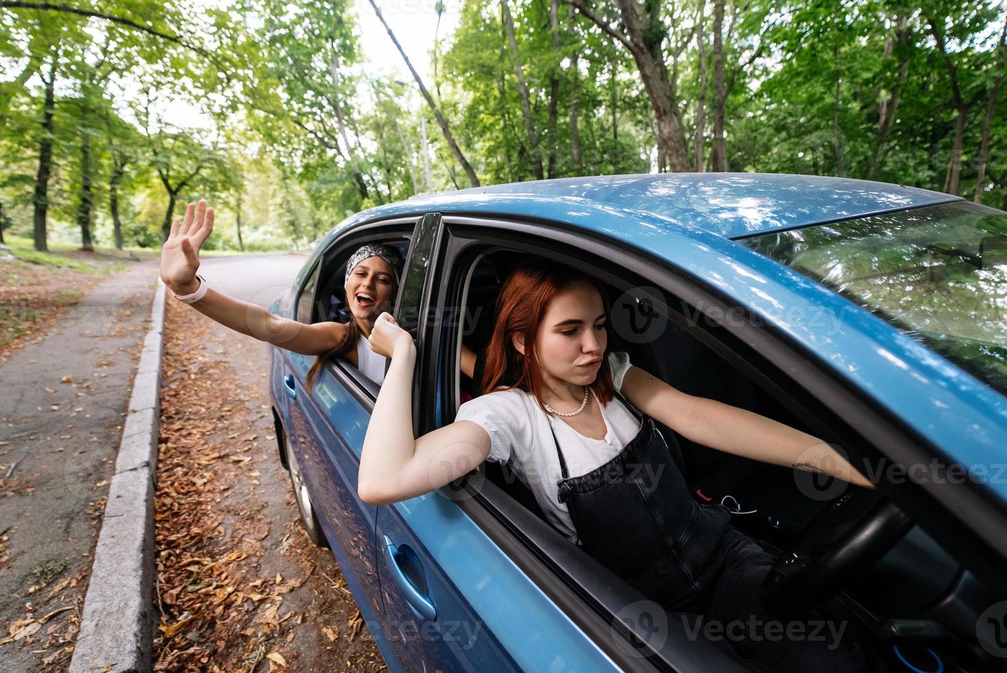 Two girlfriends fool around and laughing together in a car photo