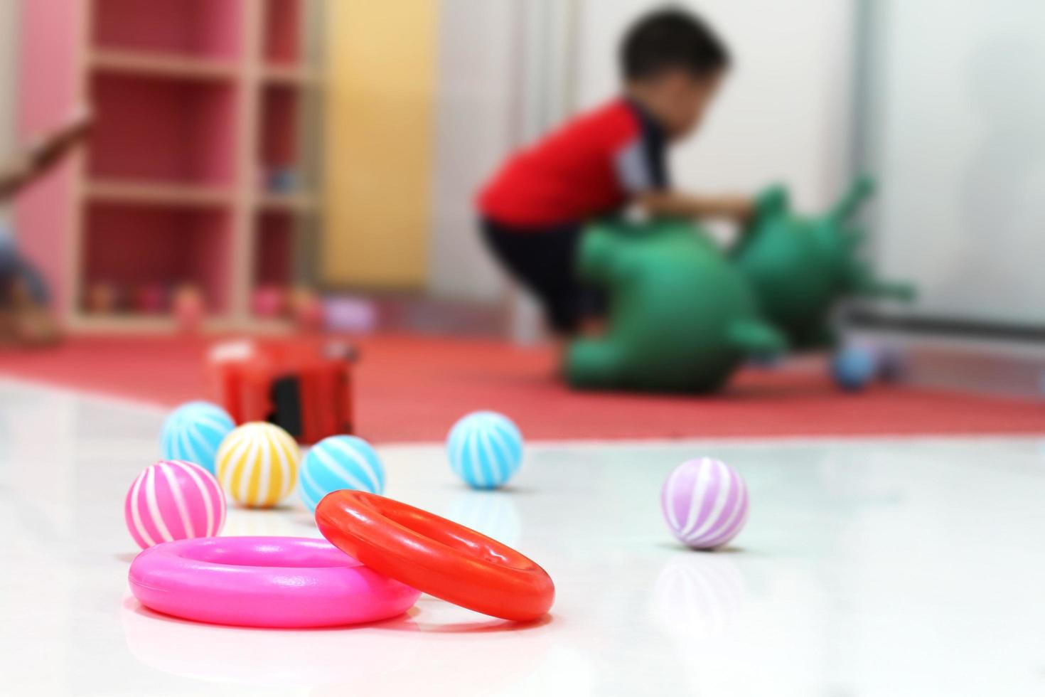 Toys placed on the floor with the blurred of a little boy playing with dolls. photo