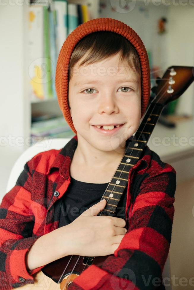 boy in a red hat and a plaid shirt plays the balalaika. photo