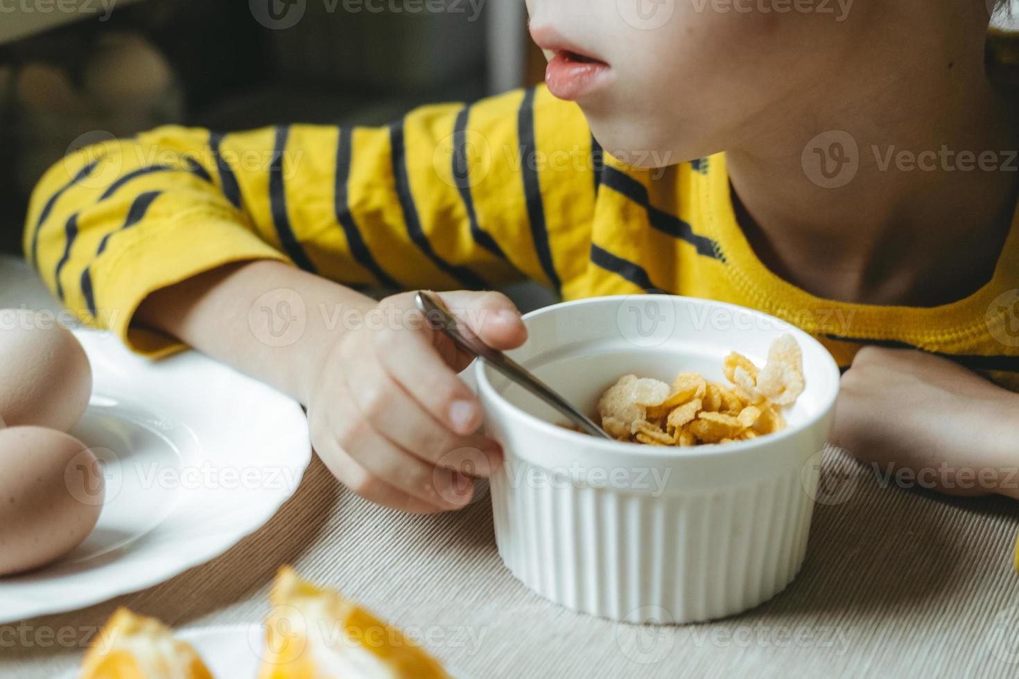 boy eats breakfast in the morning with cereals with milk. flakes close-up photo