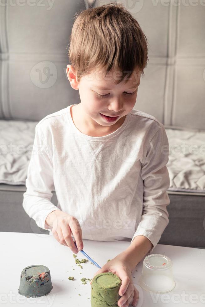 boy play with Kinetic sand at home. Development of fine motor skills. sand antistress for children. Games that calm the nervous system. Colorful sand for games photo