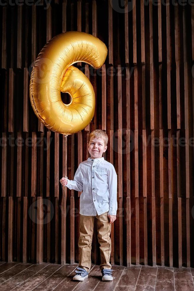 birthday boy in a photo studio with a ball number 6. boy at the birthday party. decoration with balloons. smart boy at a party