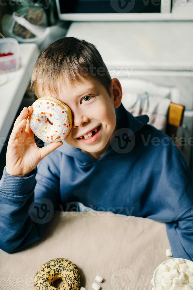 chico divertido con donut. el niño se está divirtiendo con donut. comida sabrosa para niños. tiempo feliz en casa con comida dulce. foto