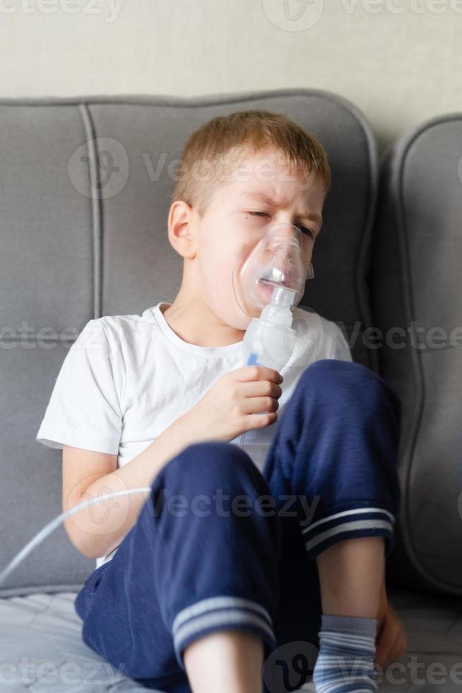 A little boy sits with an inhalation mask during cough and bronchitis photo