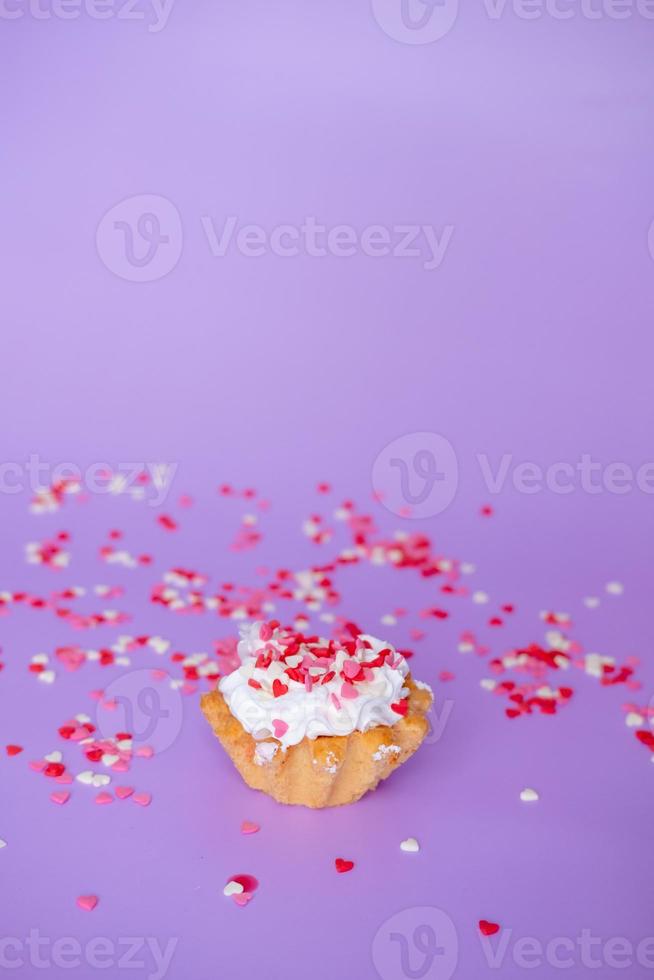 cake with whipped cream studded with small hearts on a purple background. Valentine's day and birthday concept photo