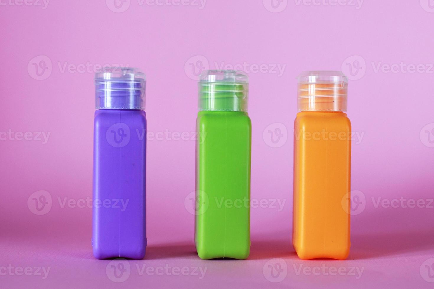 Isolated spa cosmetic products, multicolored tubes, on a pink background. Plastic bottle for detergent cleaning agent photo