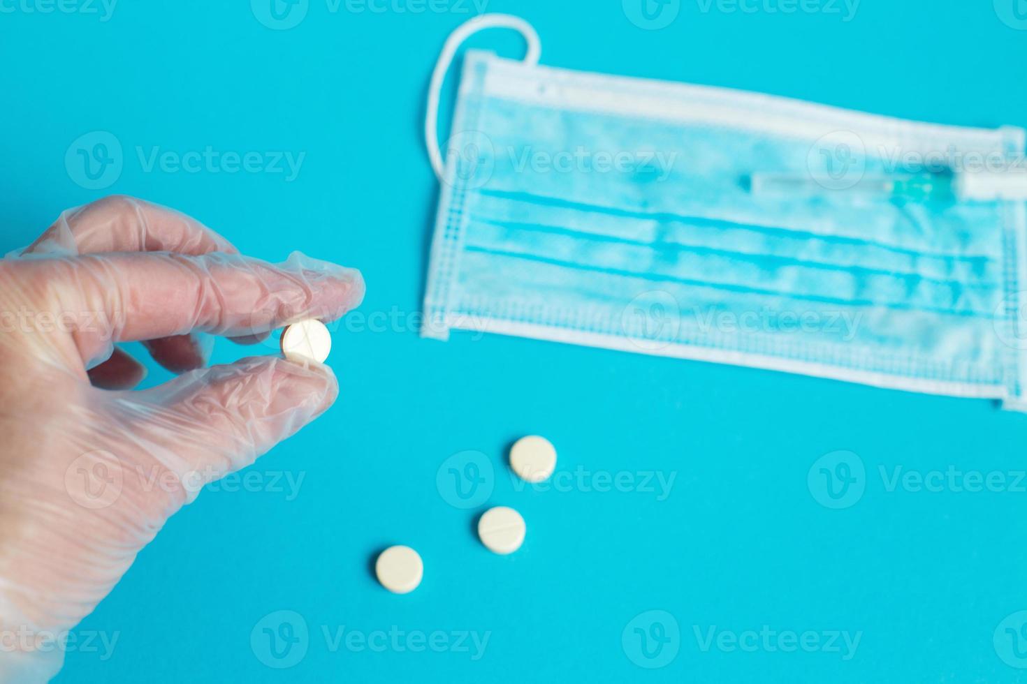 medical mask and tablets close on the blue background. hand holds pill. Coronavirus, flu respiratory disease concept photo