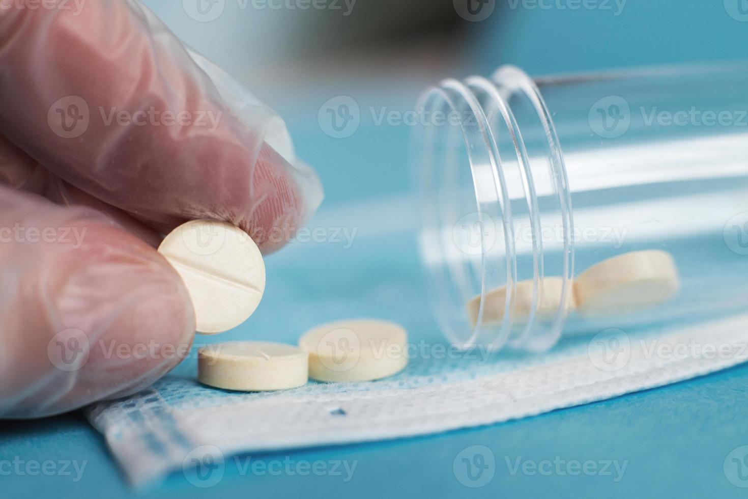 las tabletas médicas se cierran sobre el fondo azul. la mano del paramédico sostiene la píldora. coronavirus, concepto de enfermedad respiratoria gripal foto