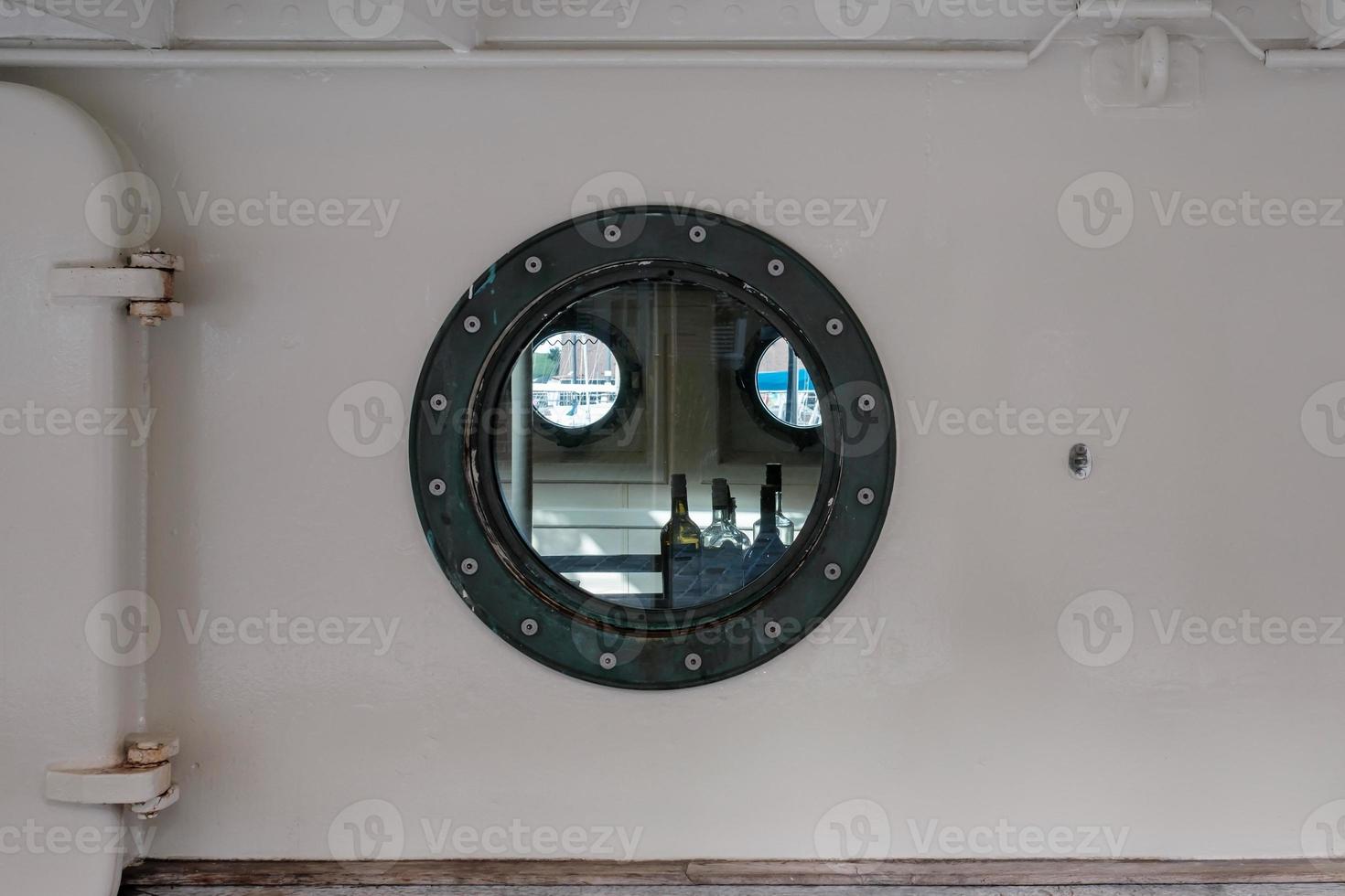 Drunkenness on ship during voyage. Alcohol bottles inside cabin visible through the porthole photo