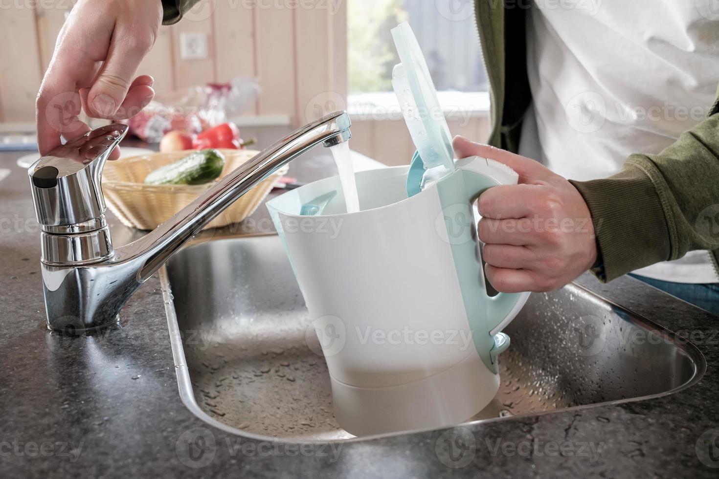 Filling with water electric kettle in the sink from the faucet photo