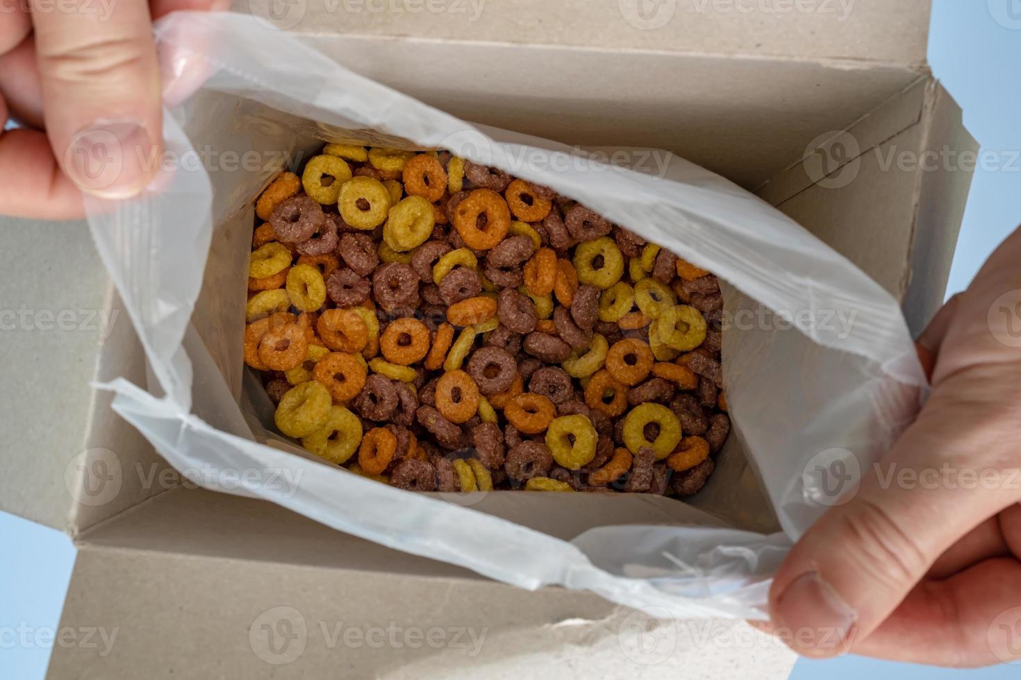 hands open a box of cereal corn rings photo