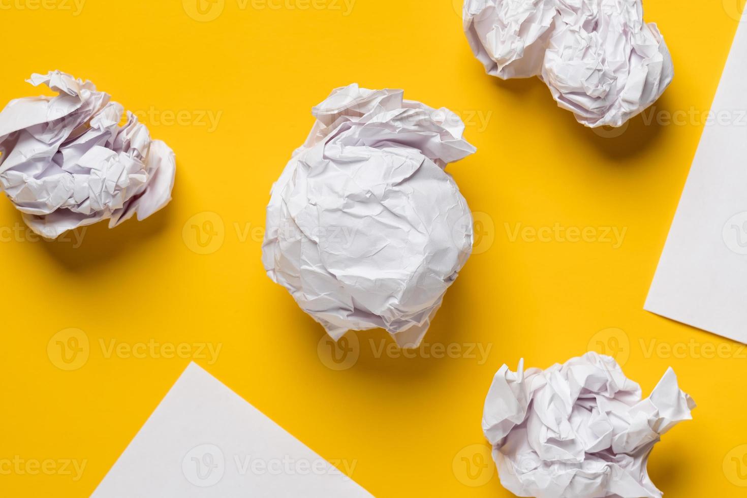 Balls of crumpled paper and white sheets of paper in the form of triangles, with space for text. Yellow background. Copy space. photo