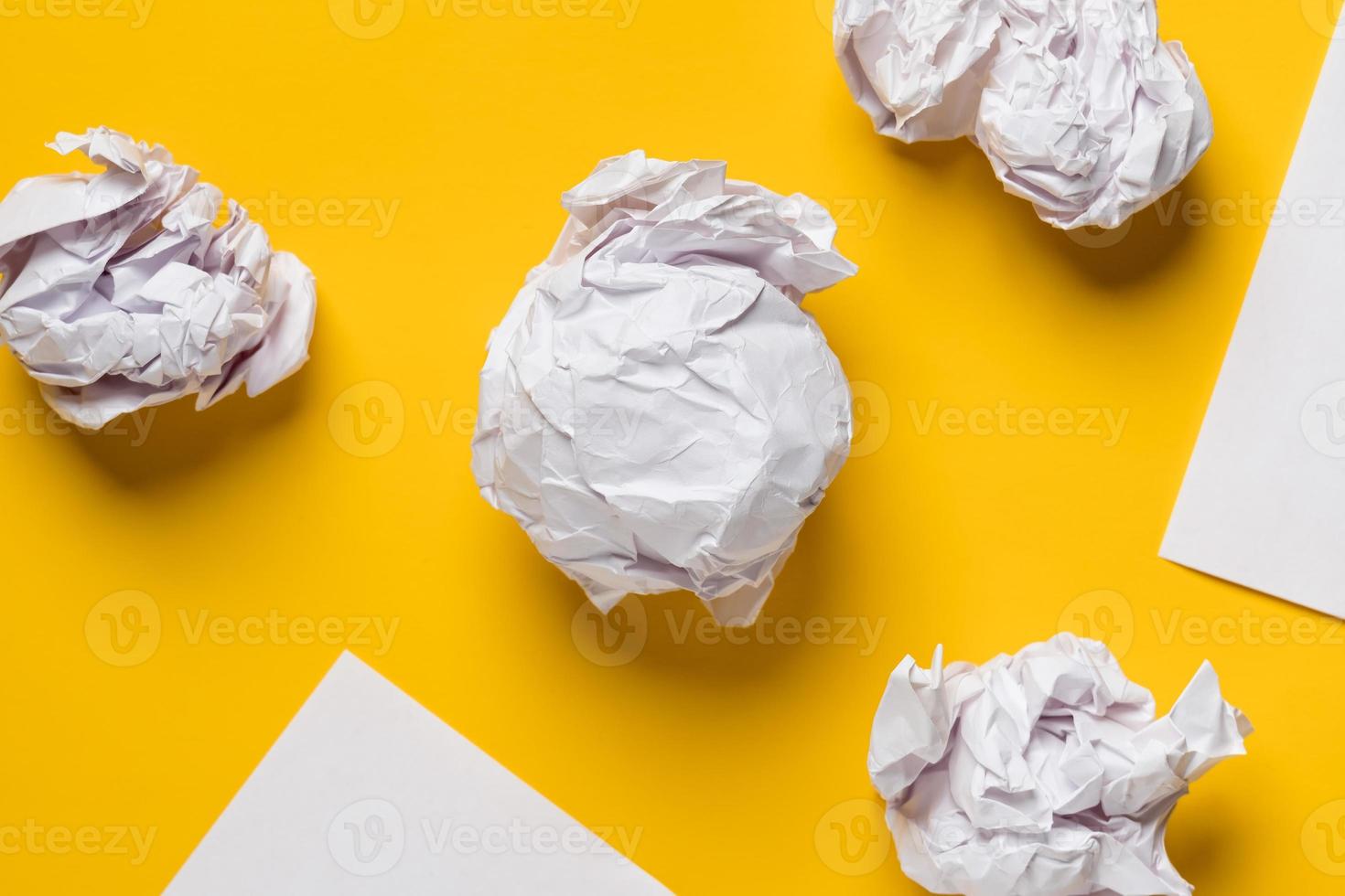 bolas de papel arrugado y hojas blancas de papel en forma de triángulos, con espacio para texto. fondo amarillo copie el espacio foto