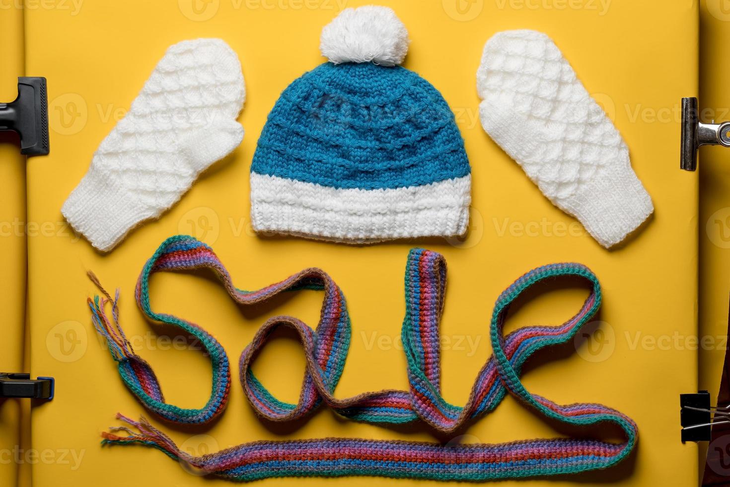 Word SALE is made with a multicolored knitted scarf, with a hat and mittens above it. Concept of New Year discounts and shopping. photo