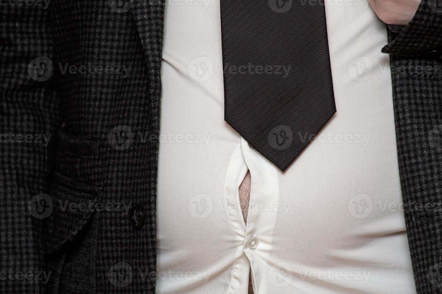 Male excess belly fat will soon rip his shirt. Overweight man. Concept of proper nutrition and a healthy lifestyle. photo