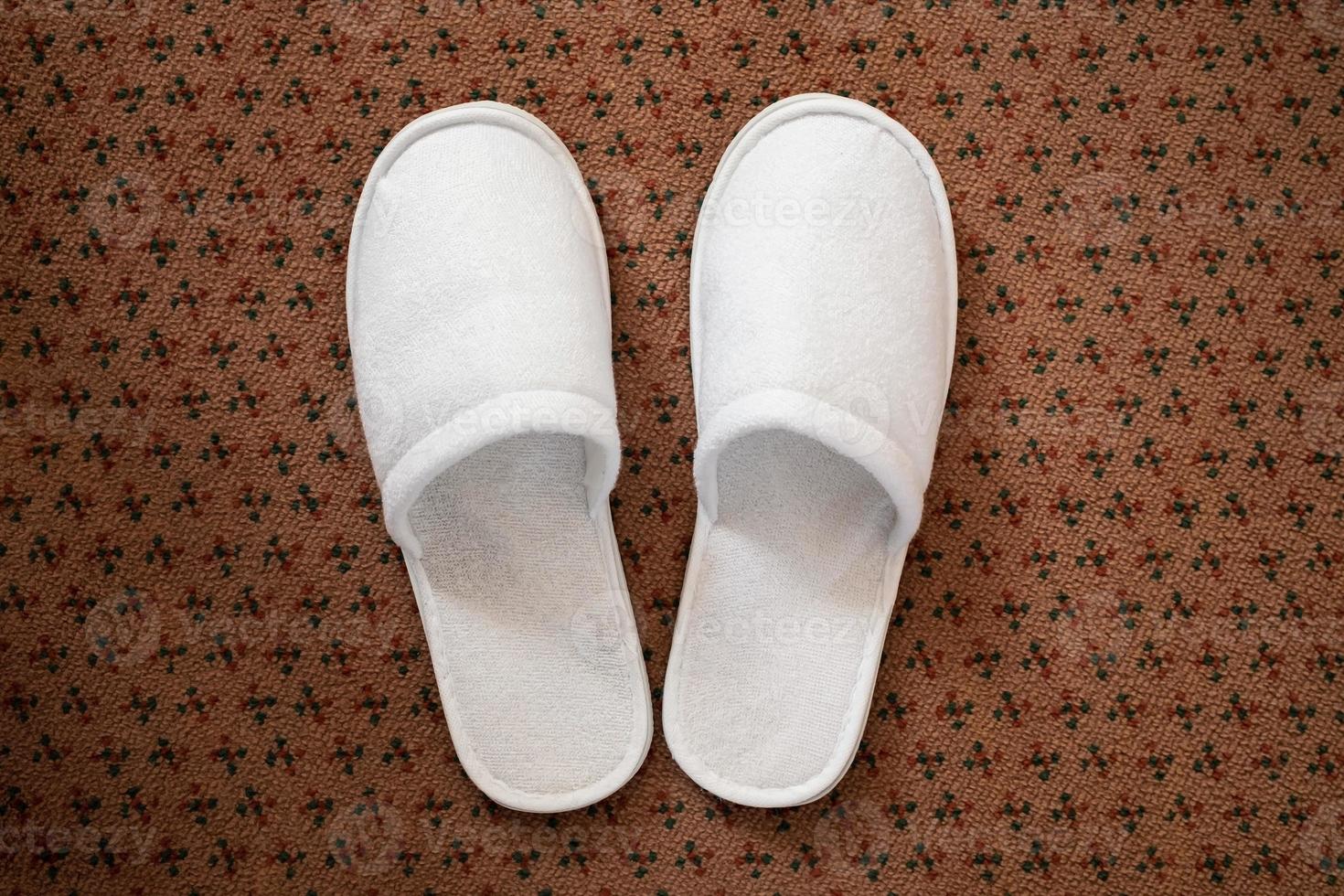 White slippers on the carpet in the hotel room. Top view. photo
