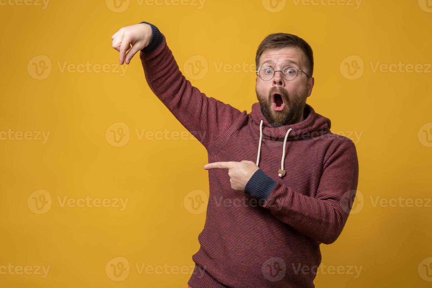 Shocked man showing fingers as if he is holding or picking up an invisible object and points at it with forefinger. Copy space. photo