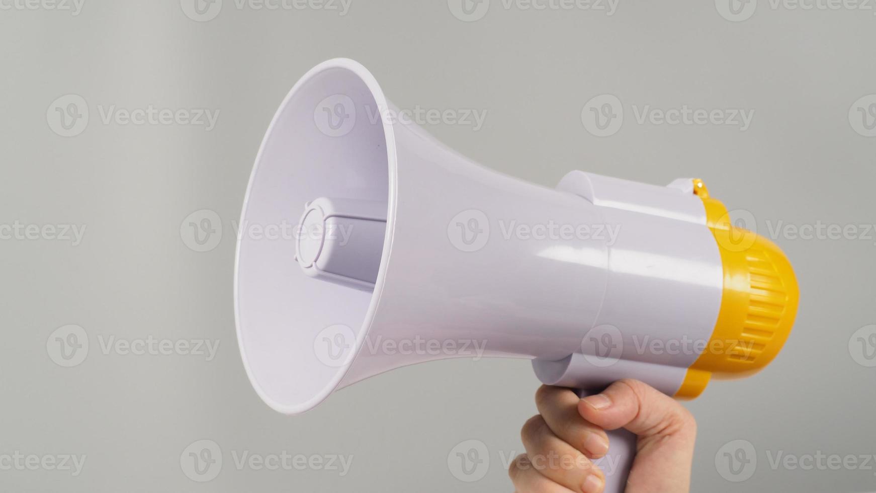 A hand is holding megaphone on grey background. photo