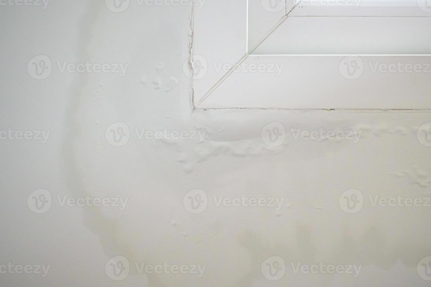 La pared de la casa cerca de la ventana con una mancha de agua muestra pintura desconchada foto