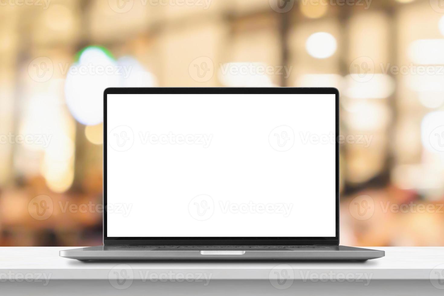 Laptop with blank screen on marble table with cafe coffee shop blur background photo