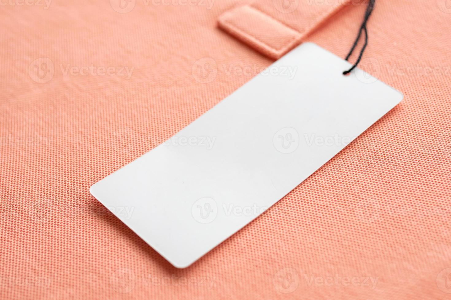 Blank white clothes tag label on pink fabric texture background photo