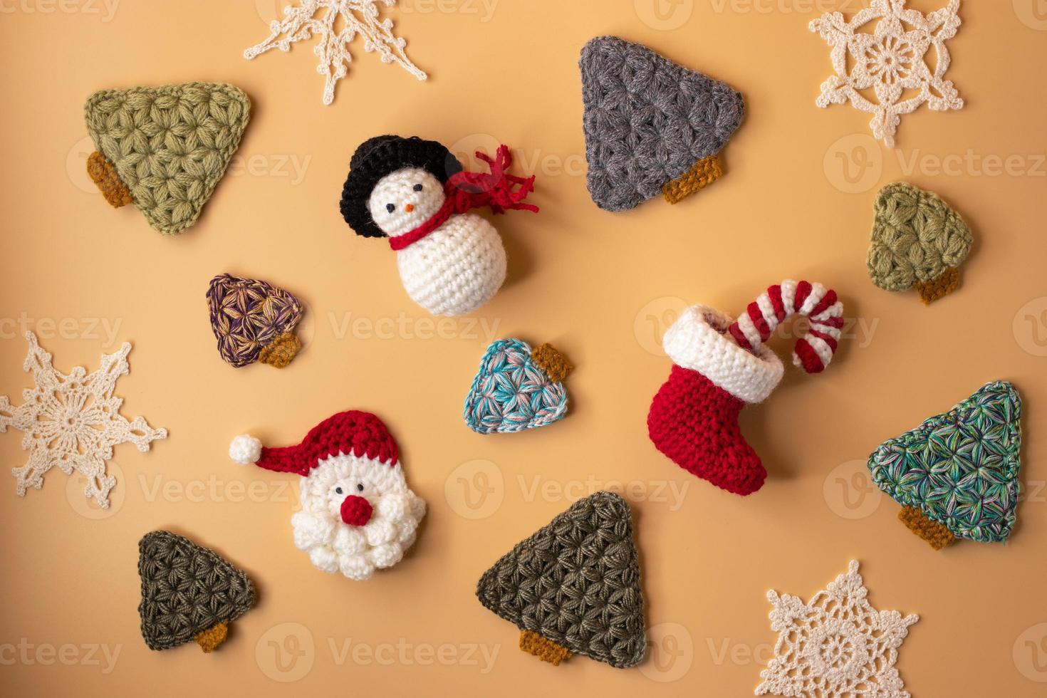 Handmade crochet stocking ,christmas tree, Candy canes, santa claus and gift on orange pastel background. Merry Christmas and happy new year concept. photo