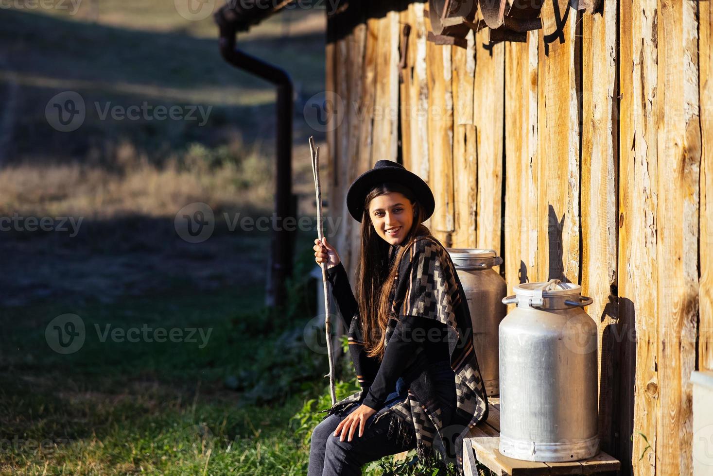 Woman sits on a bench with milk cans on a farm photo